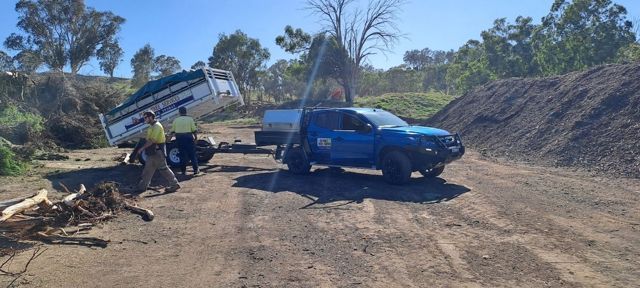 Blue pickup beside an overturned white truck on a dirt road with workers nearby under clear sky Blue pickup beside an overturned white truck on a dirt road with workers nearby under clear sky