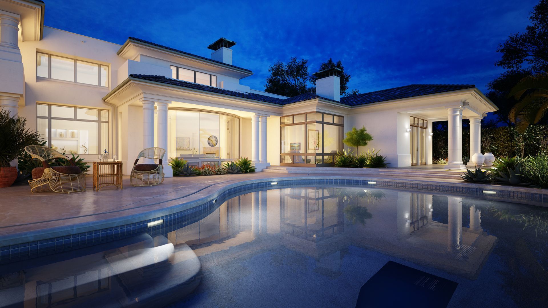 A large white house with a swimming pool in front of it at night.