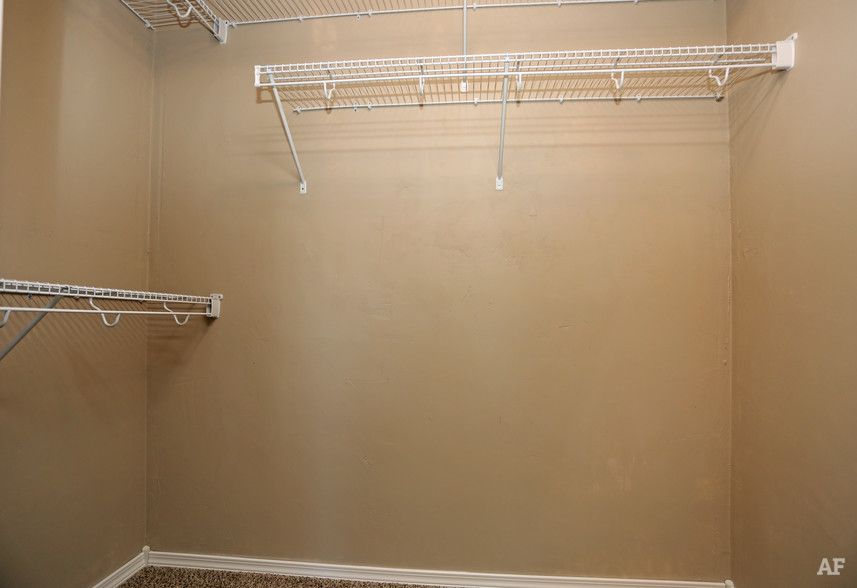 Empty beige walk-in closet with wire shelving on the walls and ceiling.