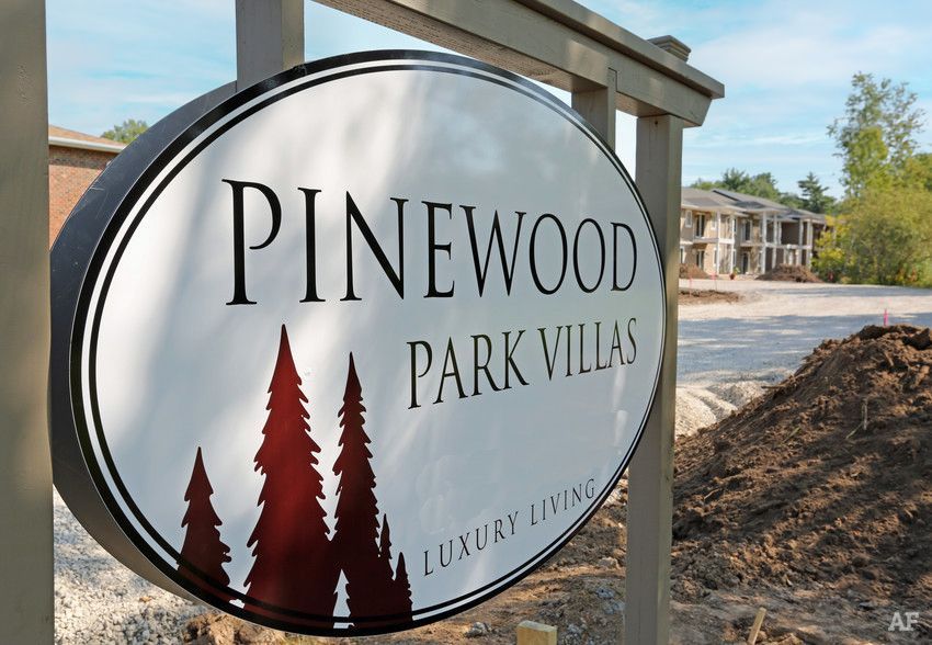 Pinewood Park Villas sign with trees in front of a building and dirt landscaping nearby
