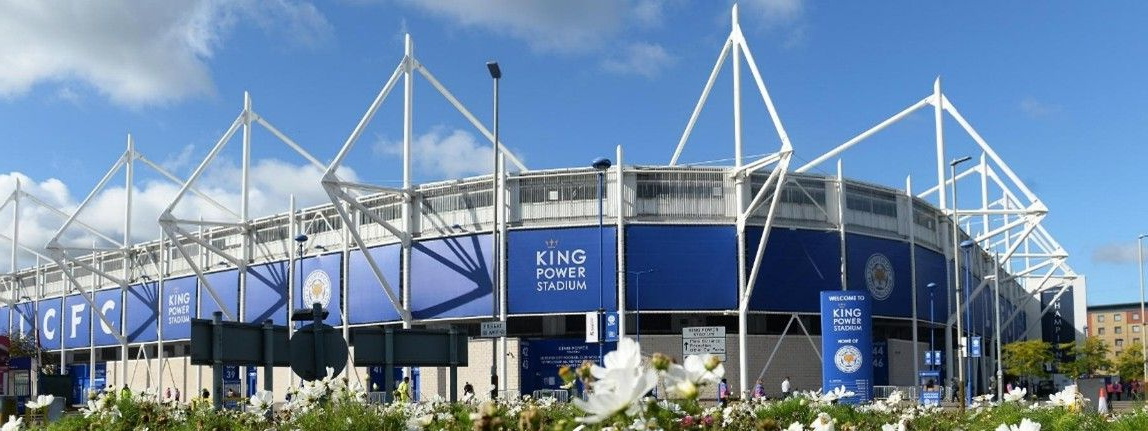 The King Power Stadium, Leicester City Football Club, under a blue sky.