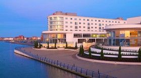 Hotel building with a waterfront view. White exterior, curved sections, glass windows, blue sky.