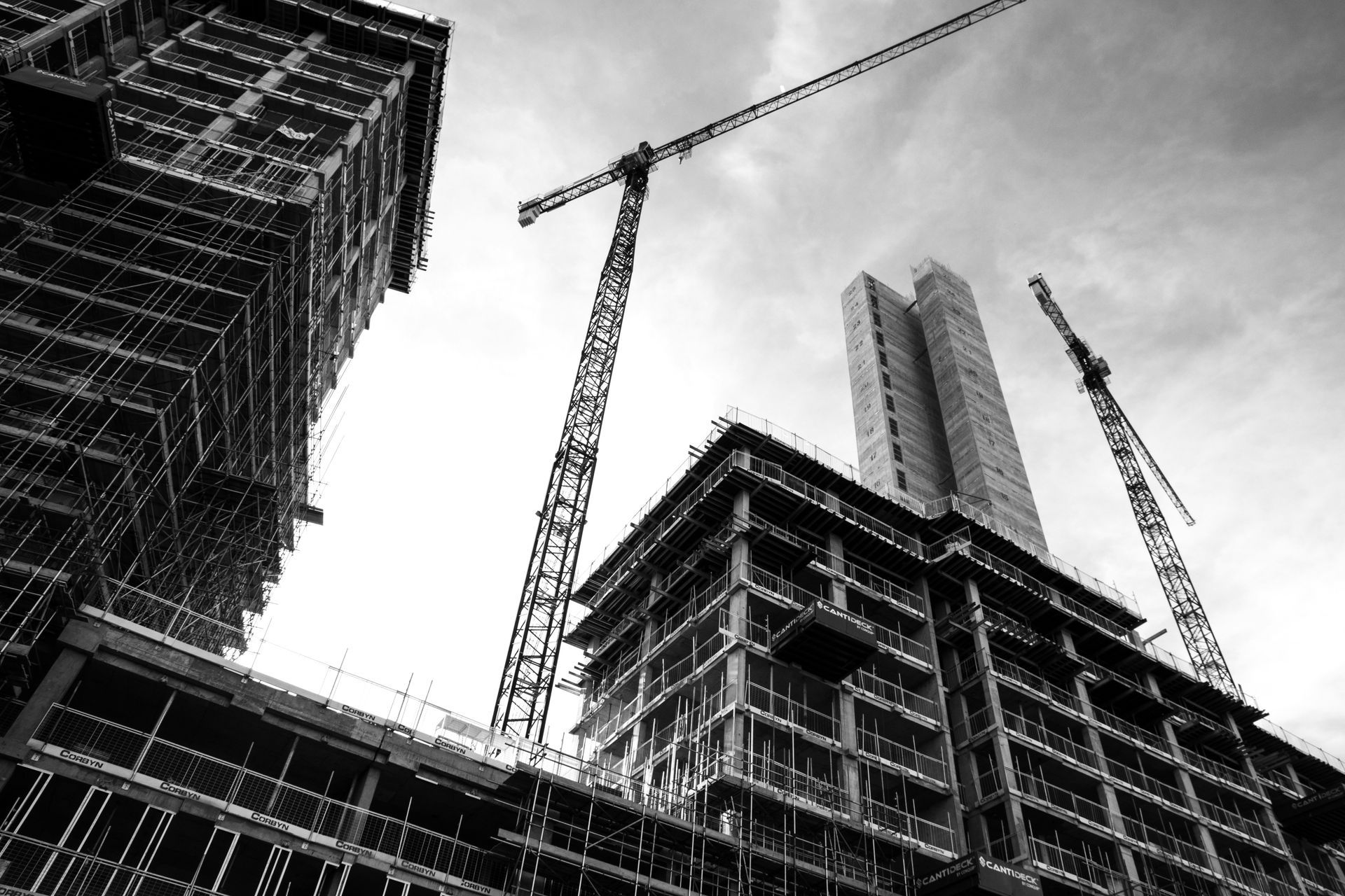 A black and white photo of a building under construction with cranes.