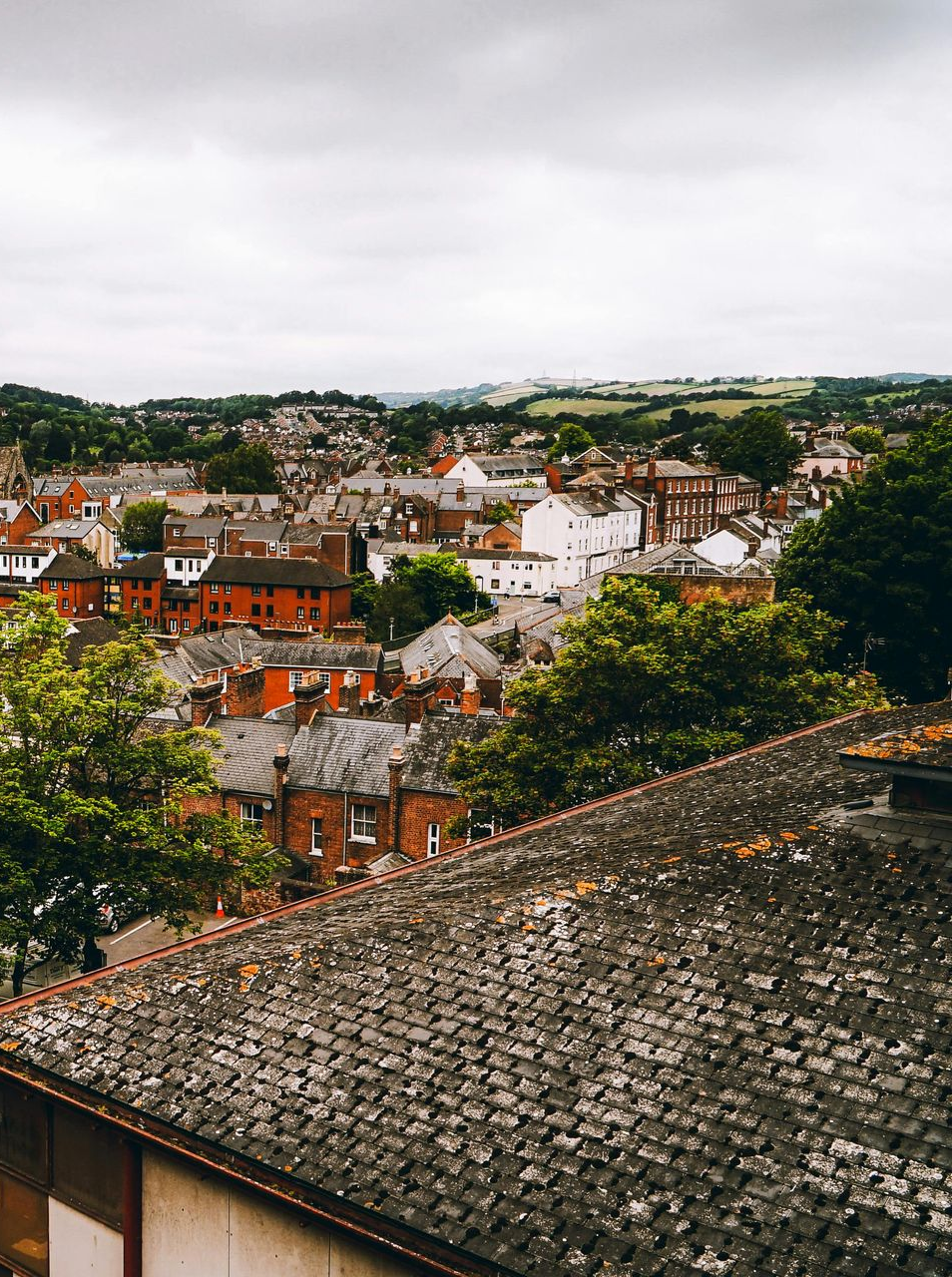 Rooftop view of a town with red brick and white buildings, under a cloudy sky.