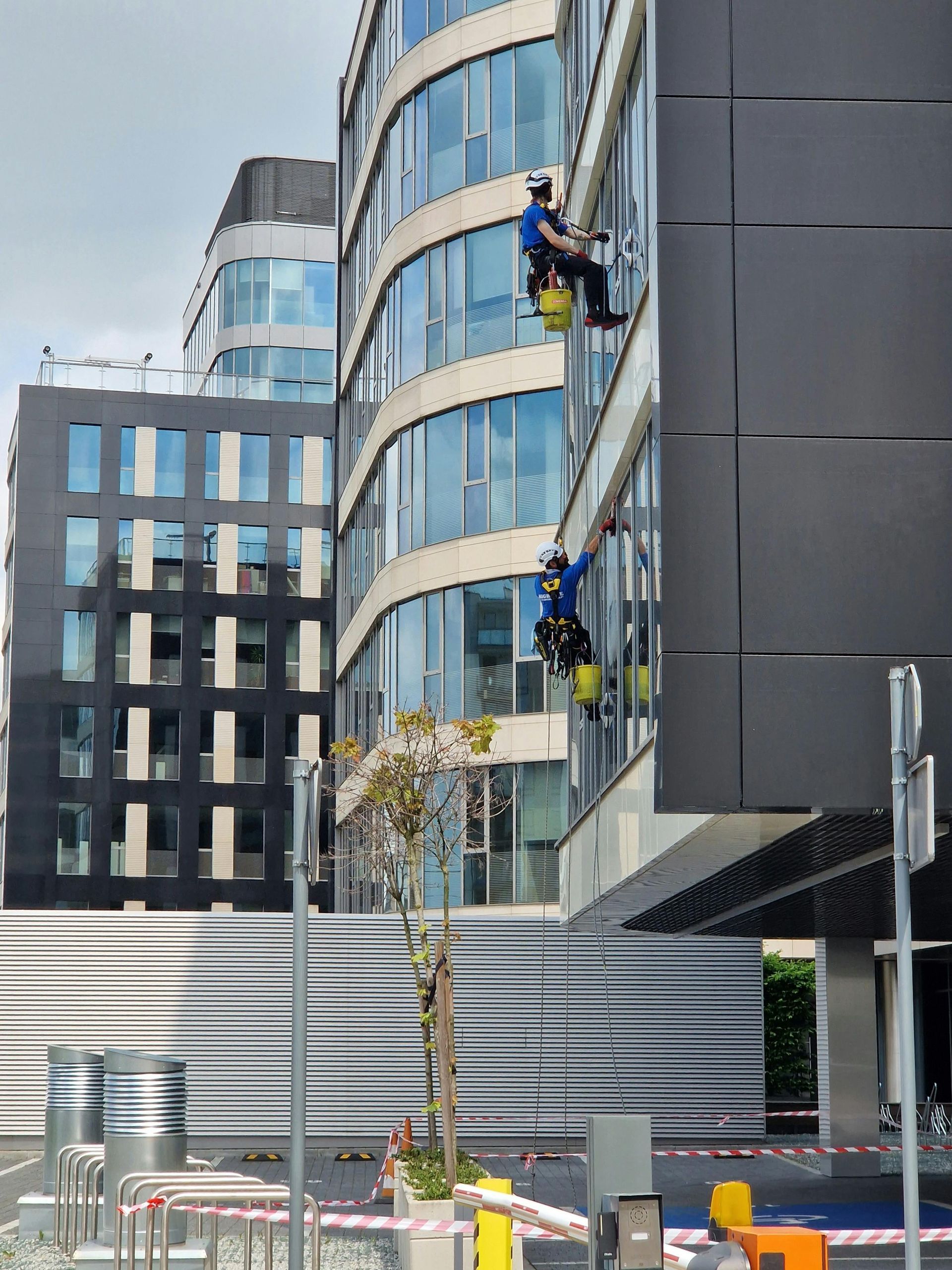 Two window washers on ropes cleaning a modern building's glass facade.