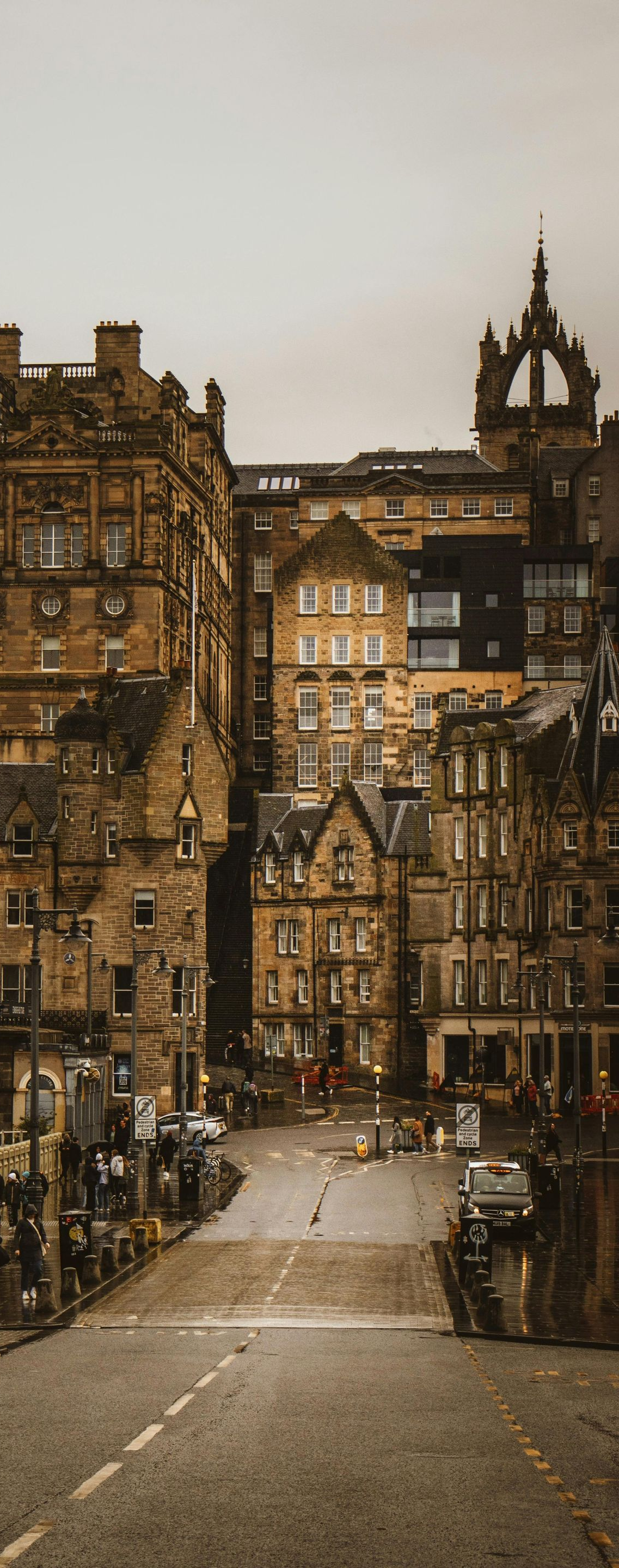 City street lined with stone buildings; cloudy sky overhead.