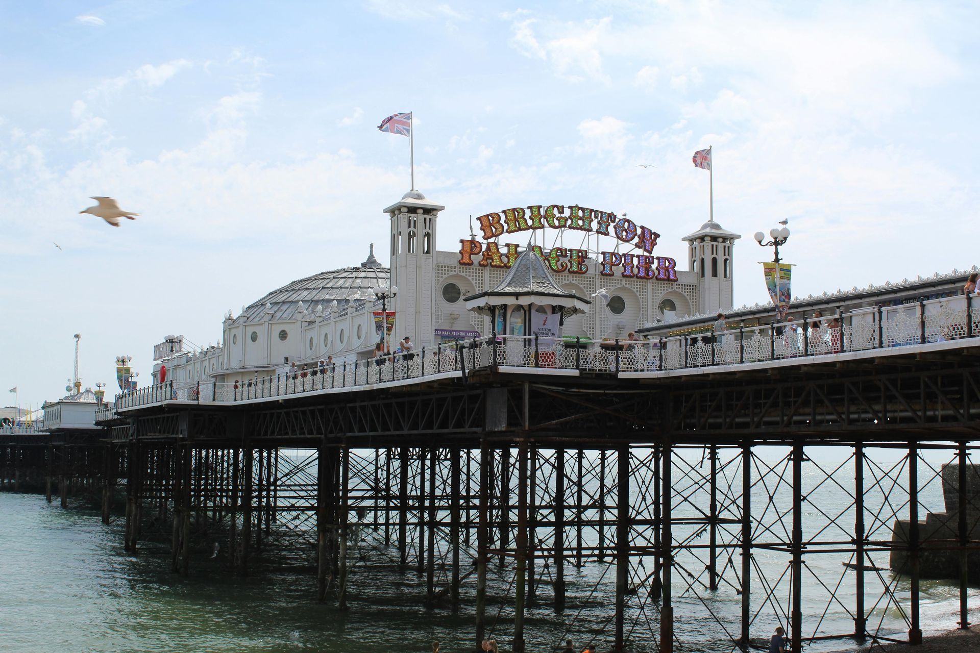 Brighton Palace Pier, a white amusement pier extending over the sea, with flags waving under a blue sky.