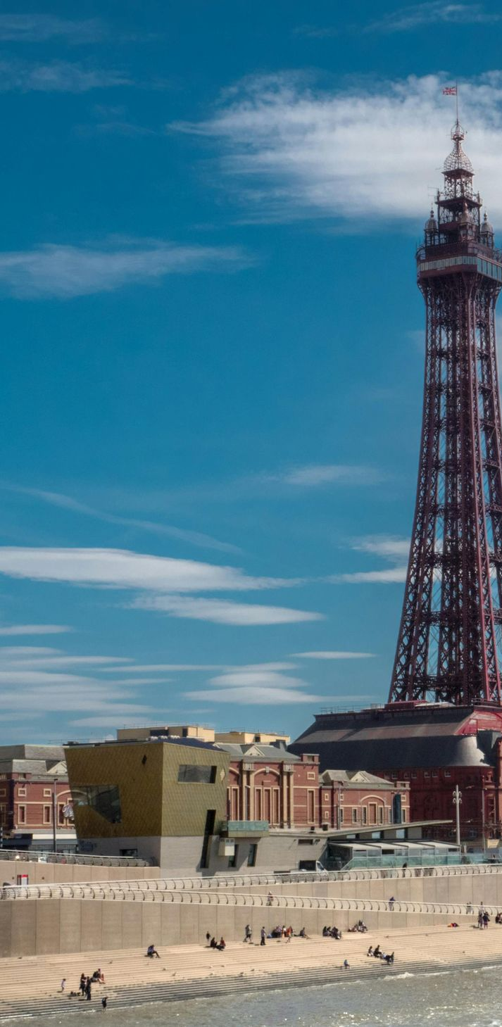 Blackpool Tower on a sunny day with blue sky and the beach in front.