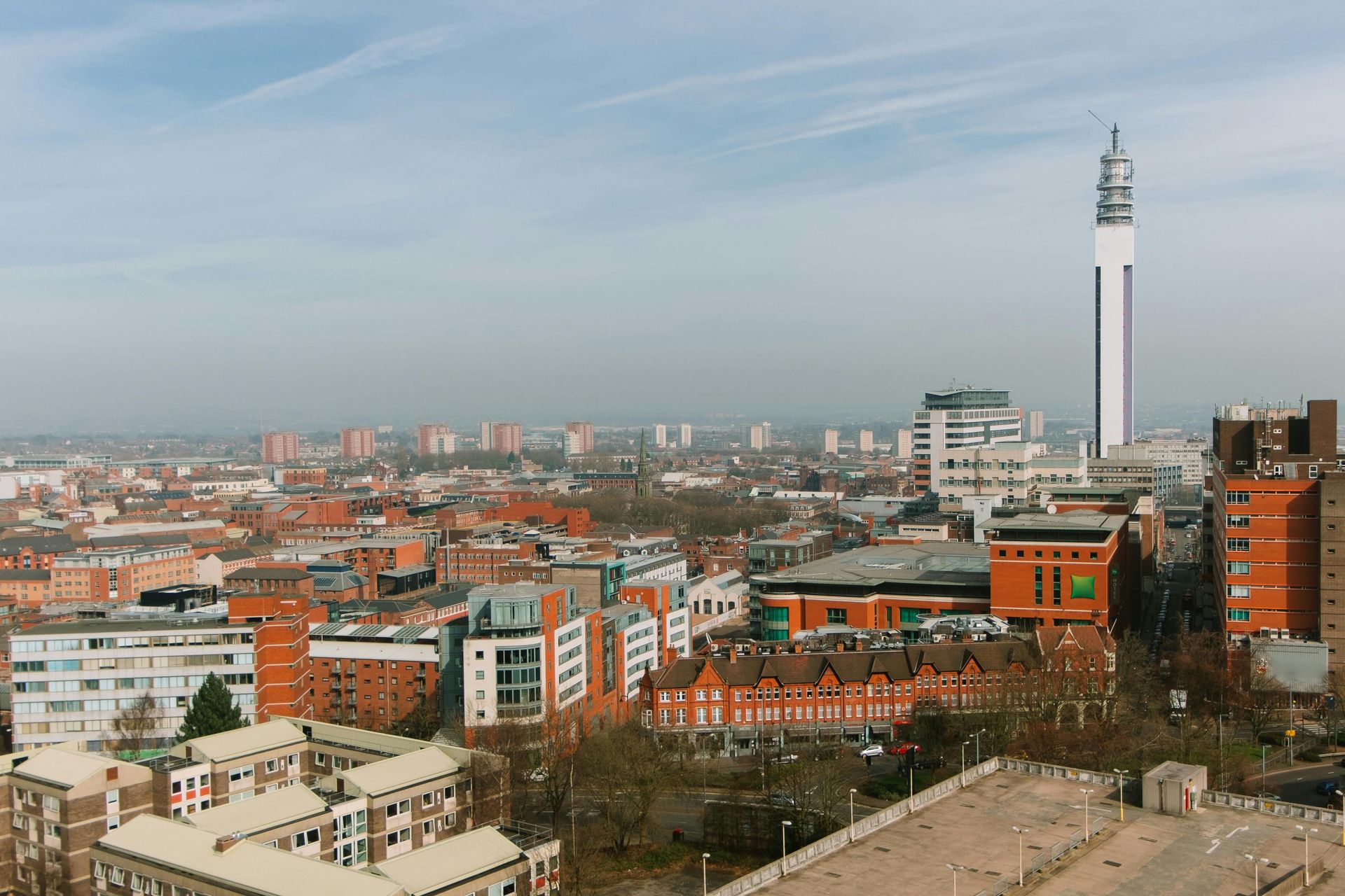 Cityscape with the BT Tower visible. Buildings are red brick and white. Blue sky.