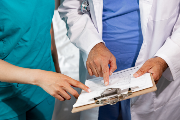 Doctor and nurse reviewing a medical chart. The doctor points at the paper; the nurse touches it.