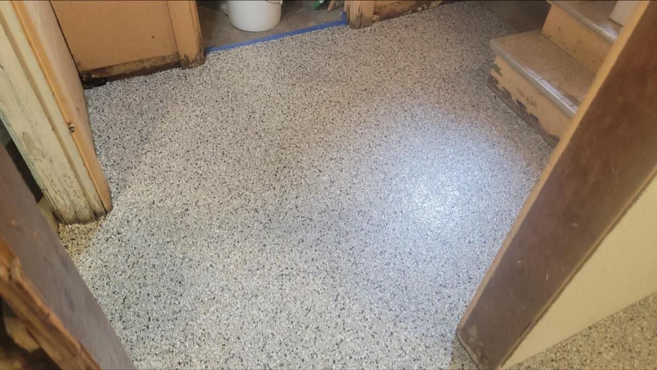 A hallway floor covered in white and black speckled epoxy flooring, seen from a doorway.