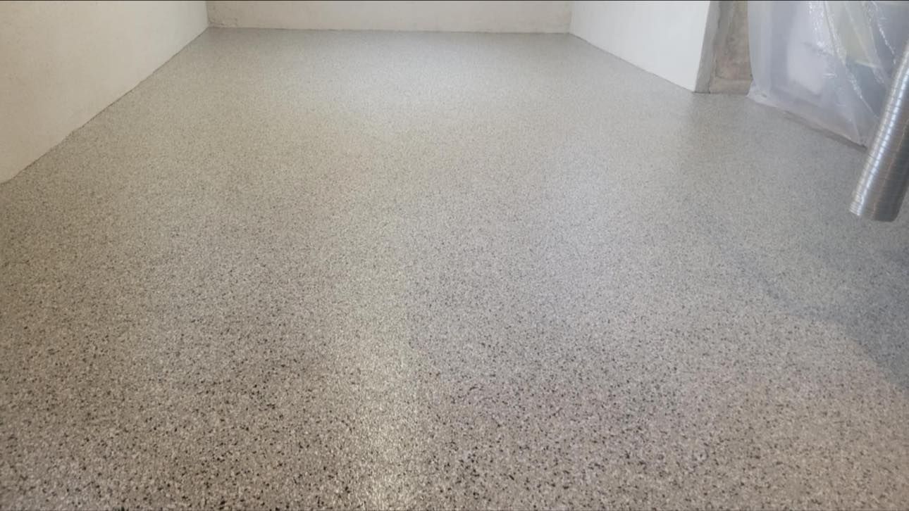 A grey, speckled epoxy floor covering an indoor room with light-colored walls.
