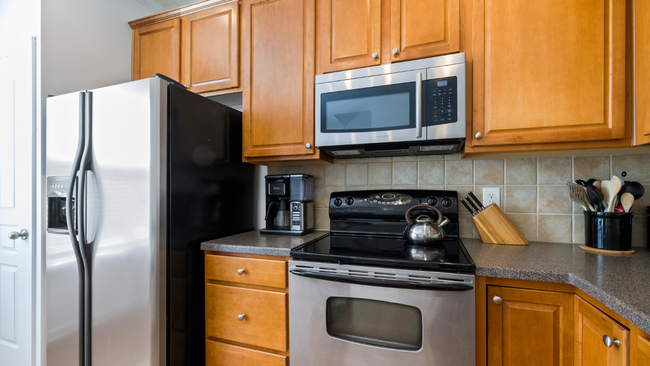 Modern kitchen with stainless steel fridge, microwave, stove, and wooden cabinets