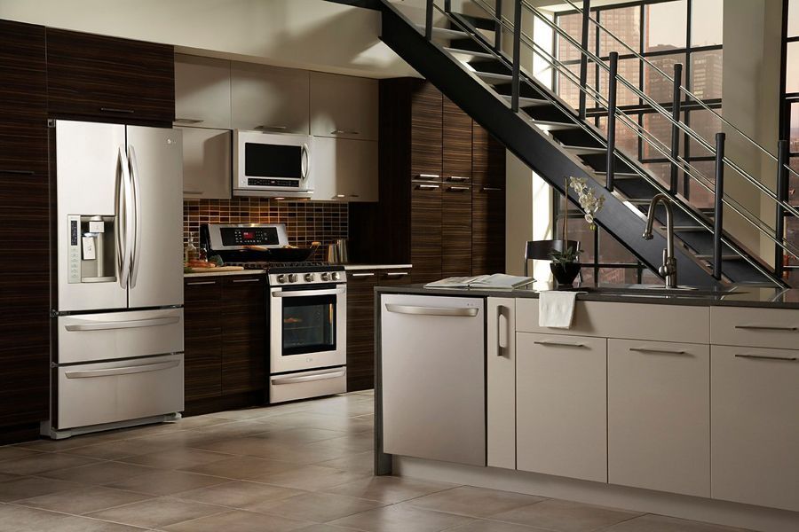 Modern kitchen with stainless steel appliances, white cabinets, and a staircase above the island