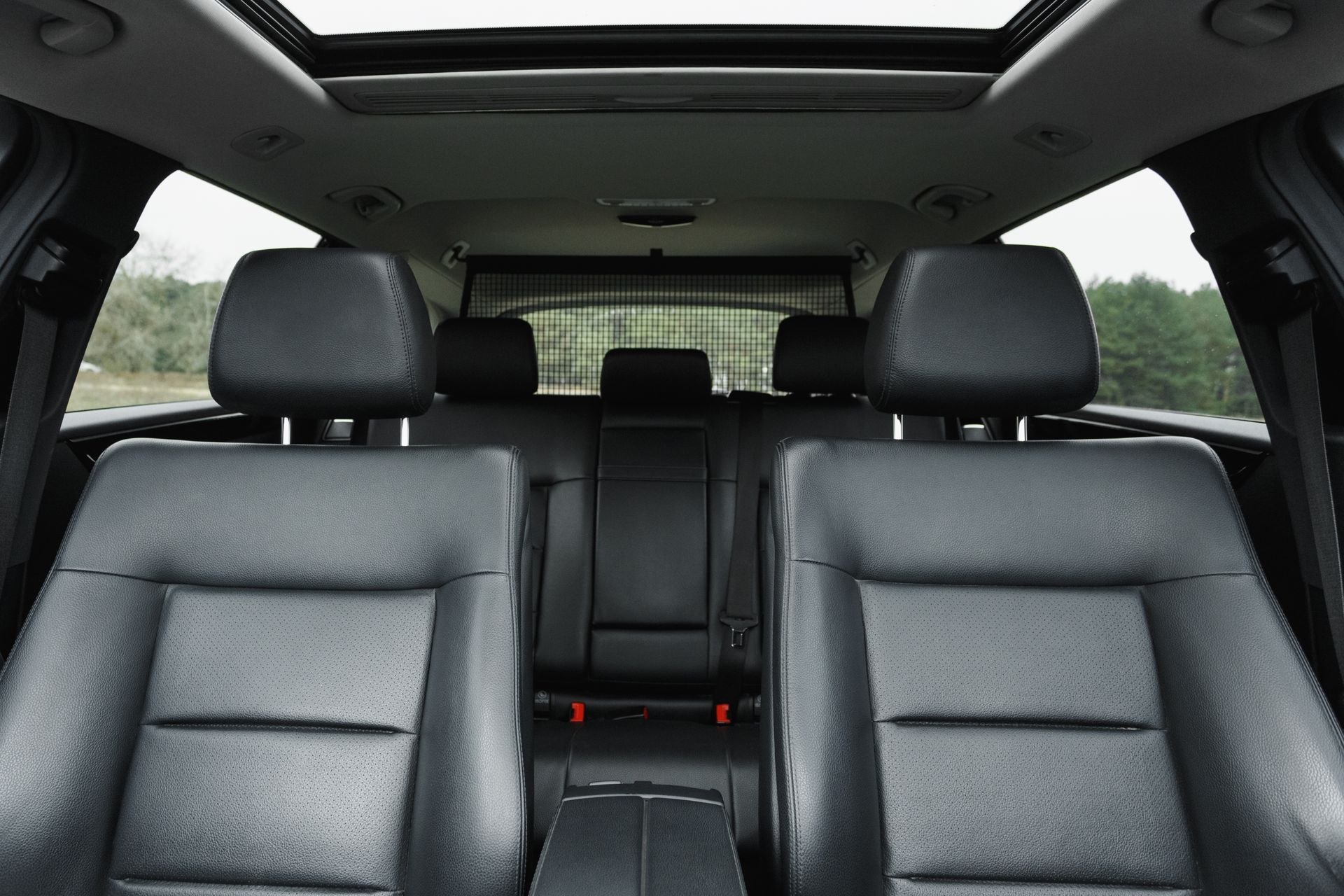 Car interior with black leather front seats and sunroof, viewed from the back seat