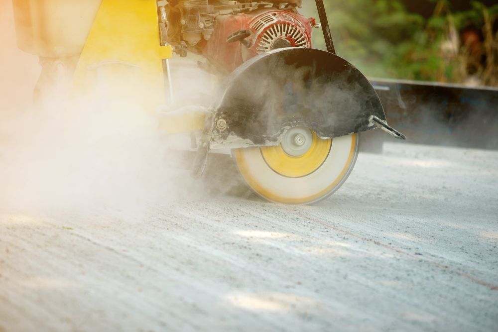 Concrete Saw Cutting Pavement, Generating Dust and Smoke — STJ Earthmoving in Kuranda, QLD