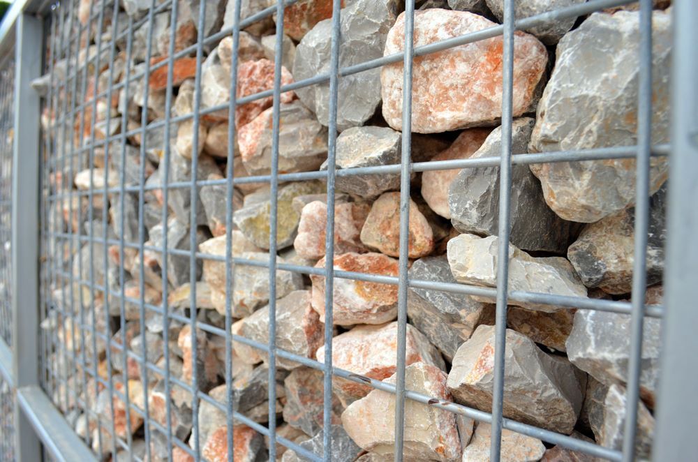 A Pile of Rocks Behind a Metal Fence — STJ Earthmoving in Weipa, QLD