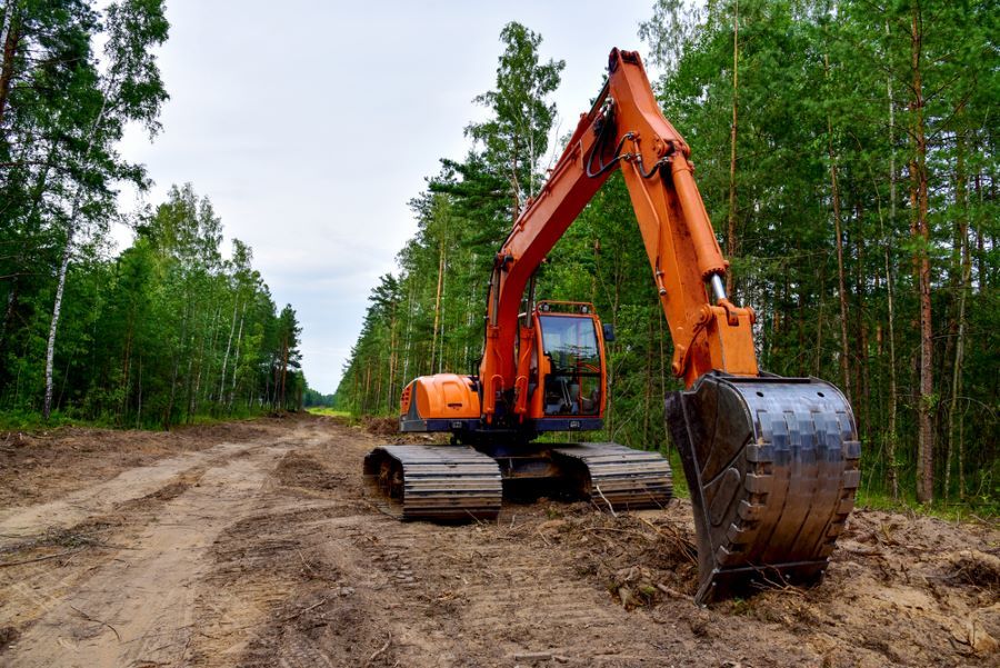 An Orange Excavator is Working on a Dirt Road in the Woods — STJ Earthmoving in Normanton, QLD
