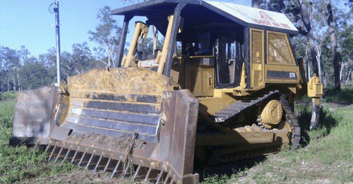 A Yellow Bulldozer is Parked in a Grassy Field — STJ Earthmoving in Mareeba, QLD