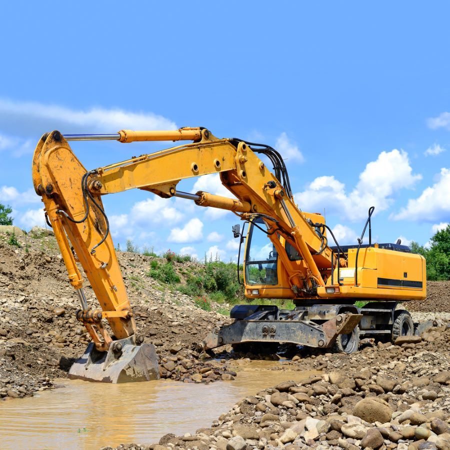 A Yellow Excavator is Digging a Hole in the Ground — STJ Earthmoving in Normanton, QLD