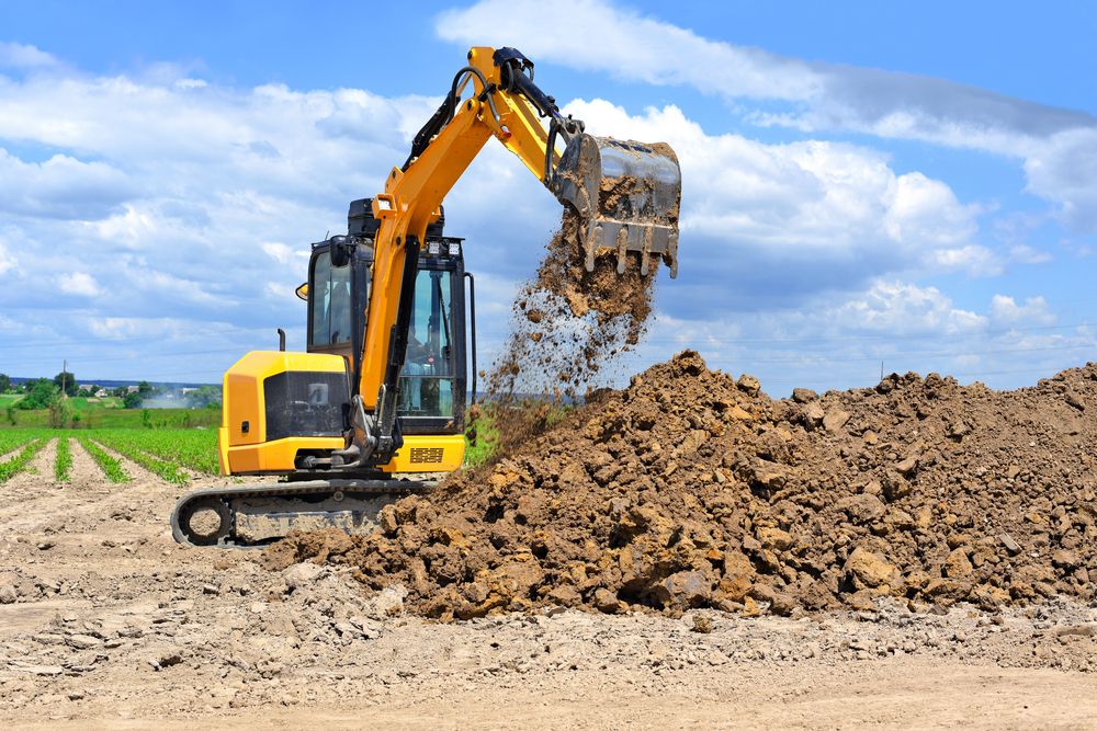 Yellow Excavator Dumping Dirt Onto a Large Pile Outdoors Under a Cloudy Sky — STJ Earthmoving in Bramwell, QLD