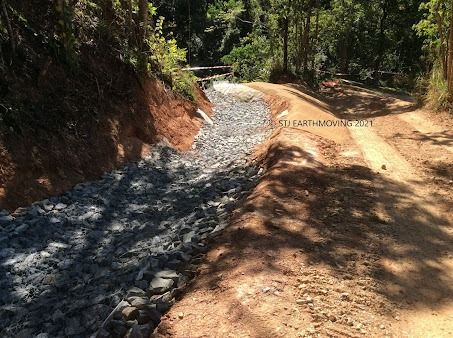 A Dirt Road Going Through a Forest With Rocks on the Side of It — STJ Earthmoving in Atherton, QLD