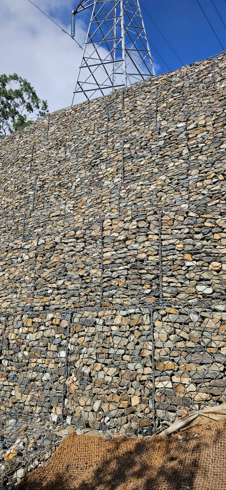 Gabion Wall Supports a Hill Under Power Lines, with Blue Sky — STJ Earthmoving in Karumba, QLD