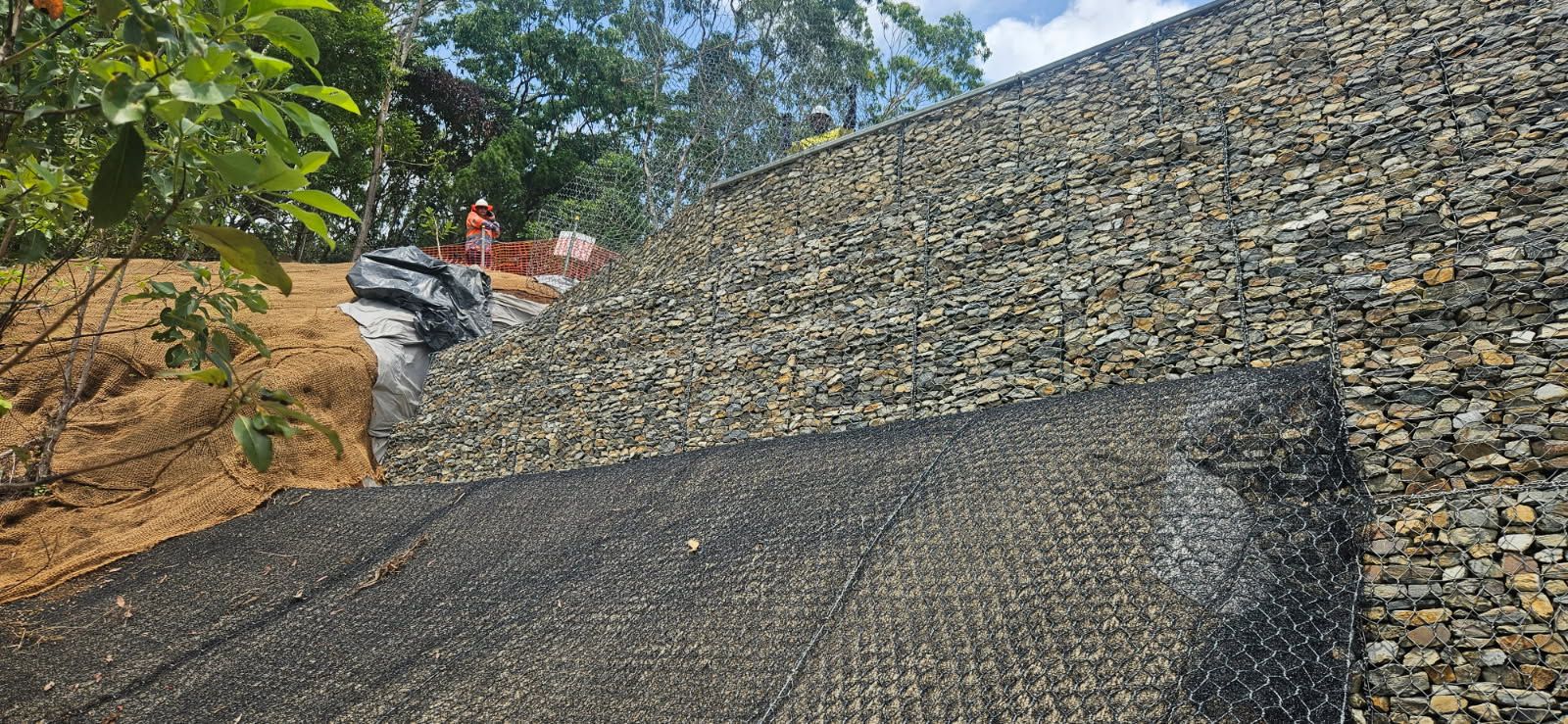 A Retaining Wall Constructed of Stone and Wire Mesh, with a Layer of Soil — STJ Earthmoving in Georgetown, QLD