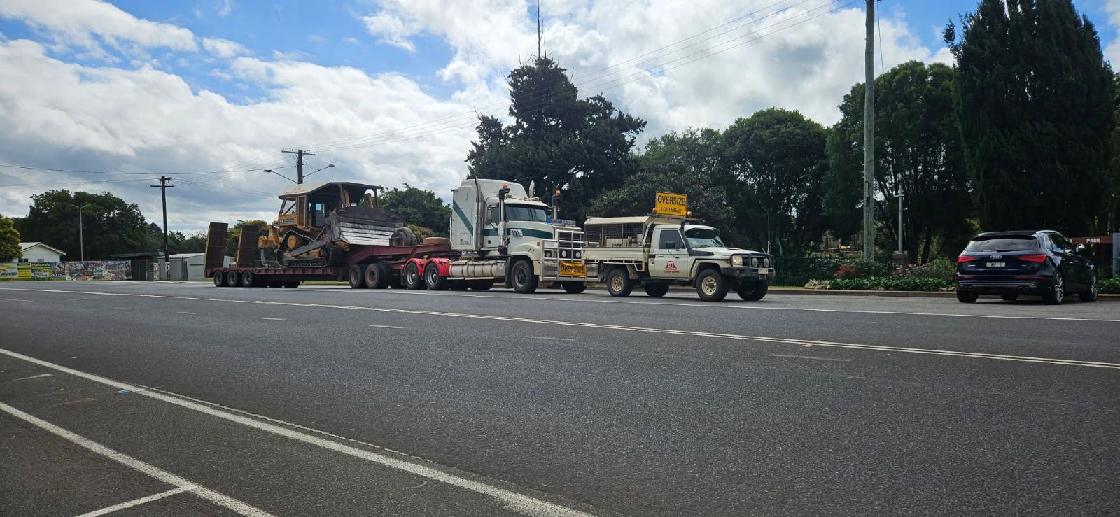 A Flatbed Truck Transporting Heavy Equipment on a Road — STJ Earthmoving in Georgetown, QLD