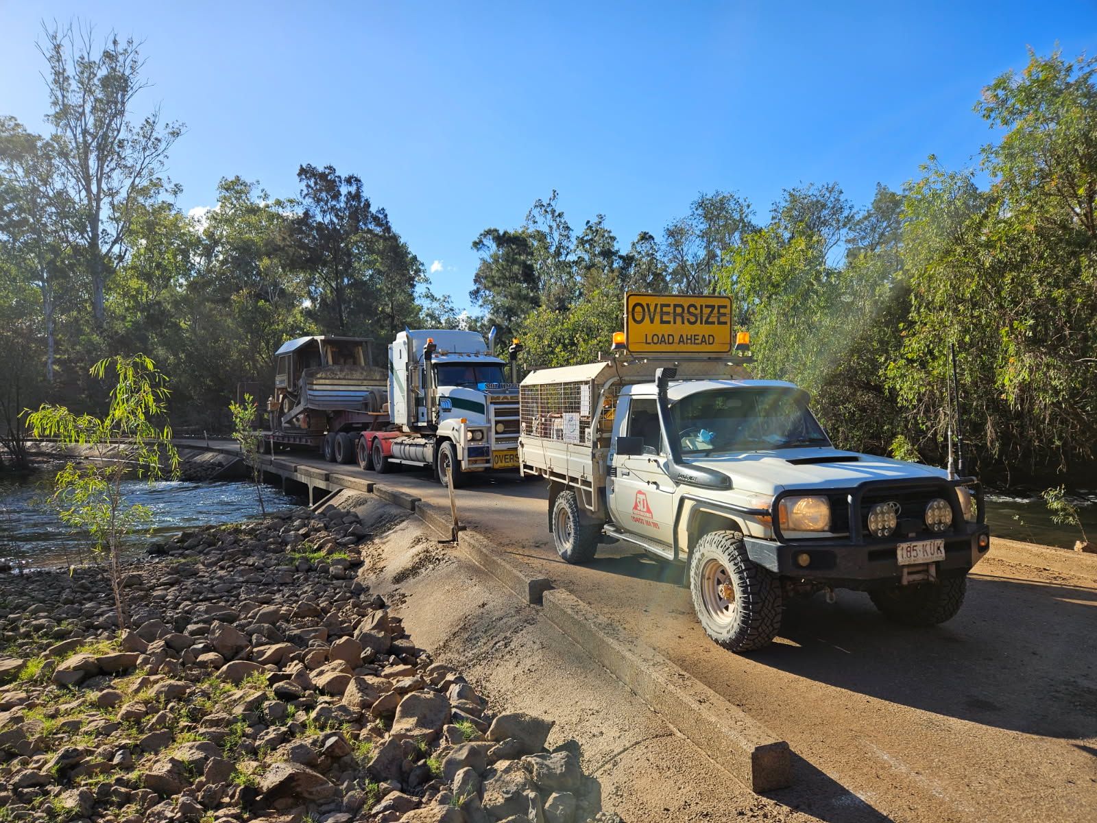 A Cat Excavator is Being Transported on a Flatbed Trailer — STJ Earthmoving in Mareeba, QLD