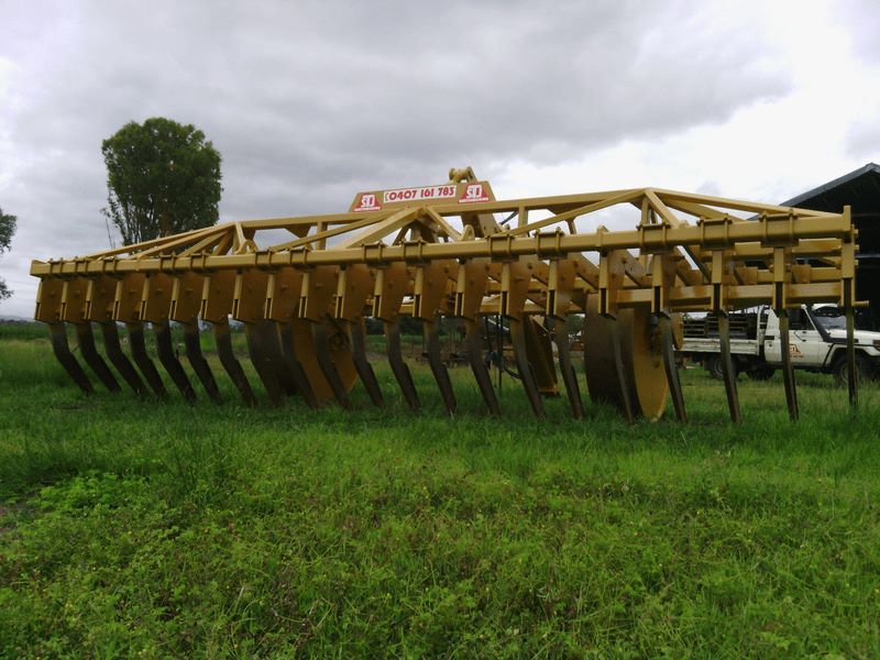A Large Yellow Tractor is Parked in a Grassy Field — STJ Earthmoving in Normanton, QLD