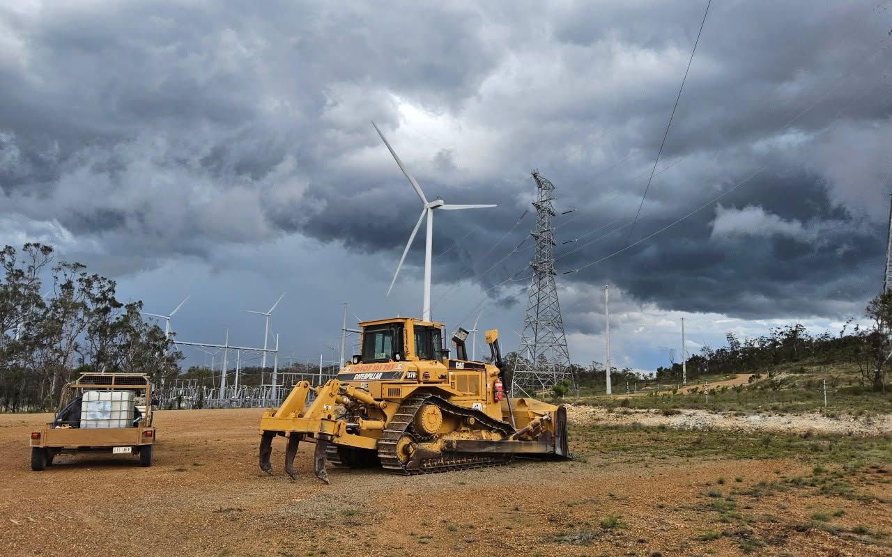 Yellow Bulldozer and Small Truck Near Wind Turbines, Under a Cloudy Sky — STJ Earthmoving in Lockhart River, QLD