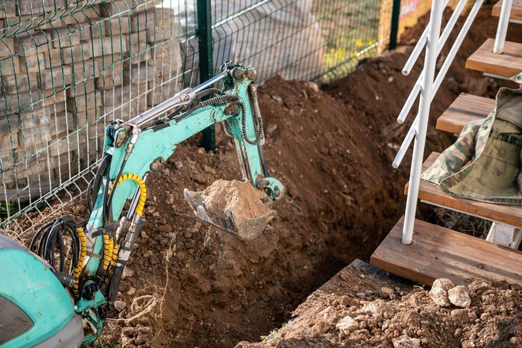 Small Excavator Digging Dirt Beside a Fence and Stairs — STJ Earthmoving in Lakeland, QLD
