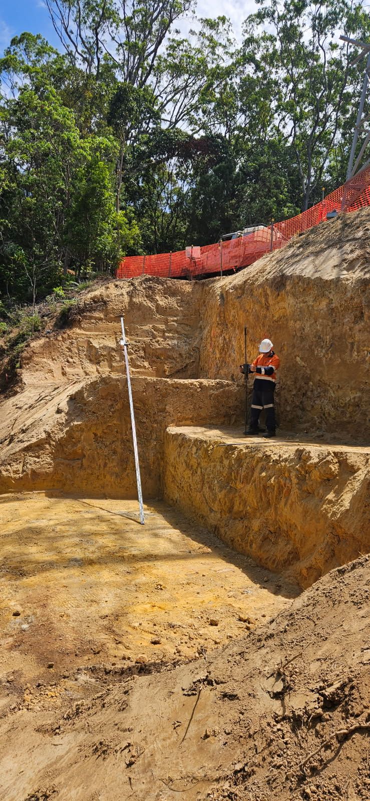 A Person in a Safety Vest Stands in an Excavated Area With a Measuring Stick — STJ Earthmoving in Kowanyama, QLD