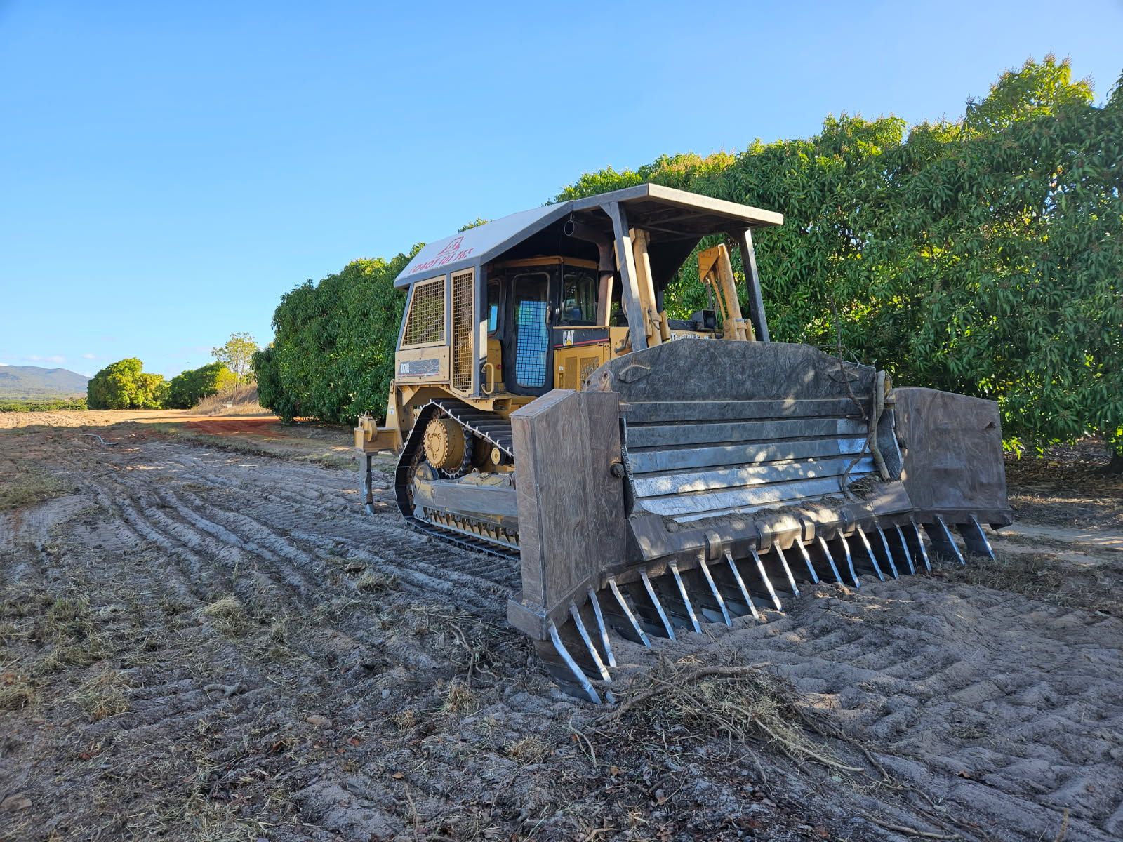 Bulldozer With Rake Blade in Field, Trees in Background, Sunny Day — STJ Earthmoving in Croydon, QLD