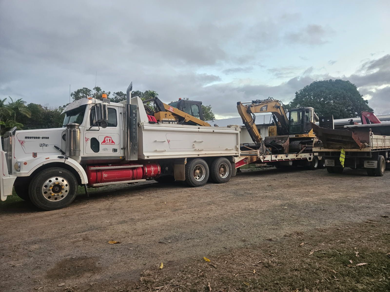 White Semi-truck With Trailer Hauling Construction Equipment — STJ Earthmoving in Archer River, QLD
