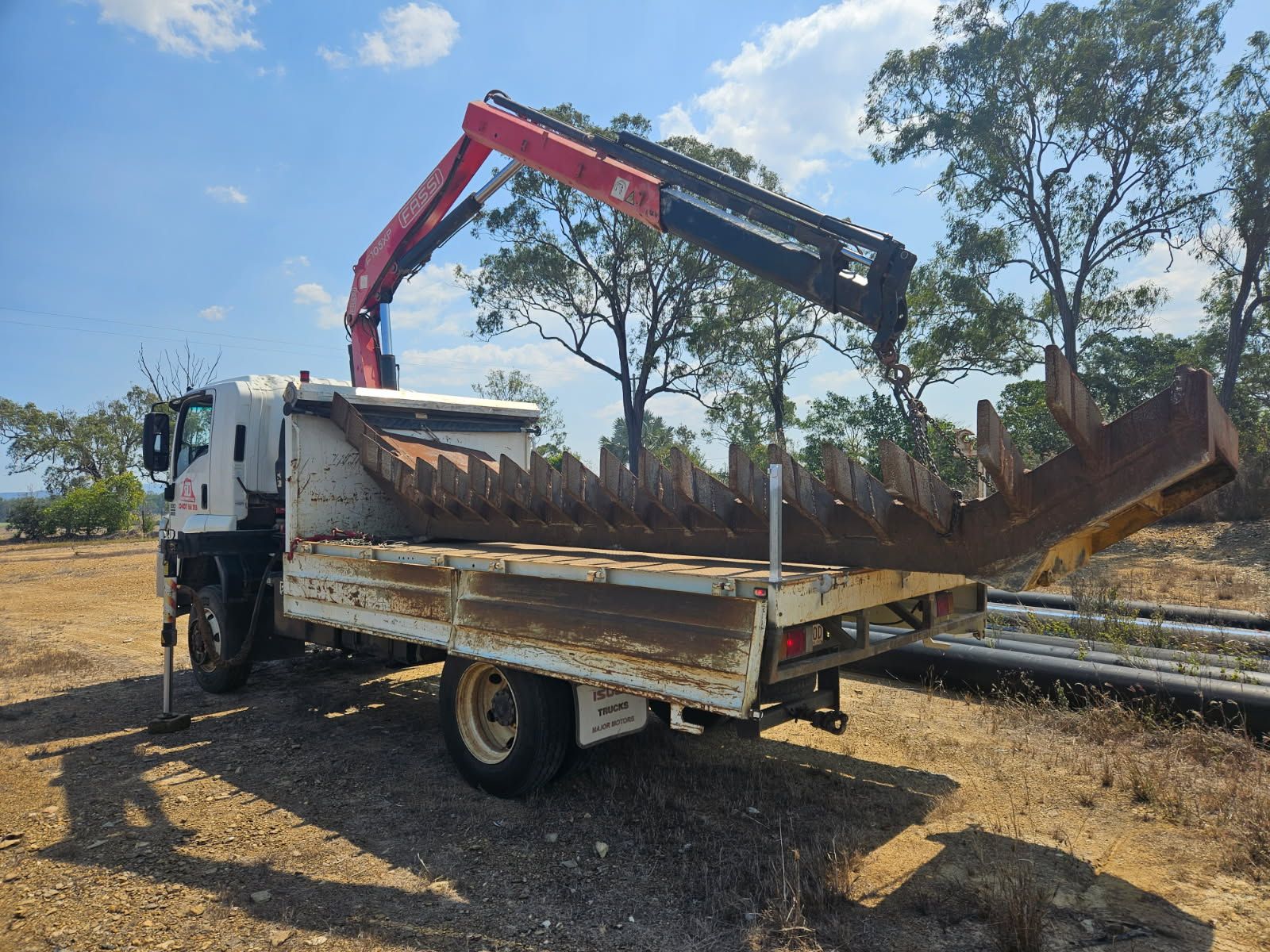 A Truck With a Red Crane Lifting a Large, Metal, Claw-like Attachment  — STJ Earthmoving in Musgrave, QLD