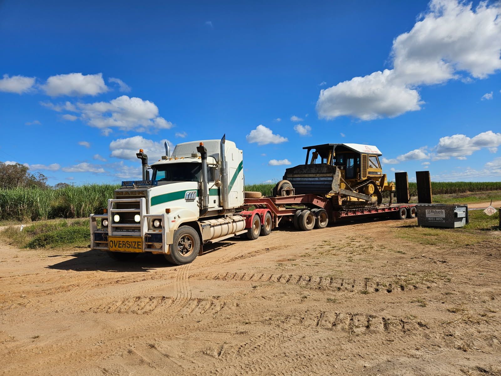 Truck Hauling a Bulldozer on a Flatbed Trailer on a Dirt Road — STJ Earthmoving in Burketown, QLD