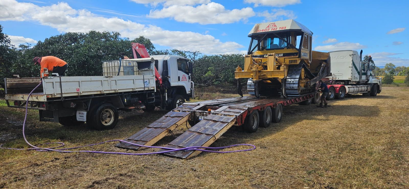 A Yellow Bulldozer on a Trailer Being Loaded by a Truck — STJ Earthmoving in Cooktown, QLD