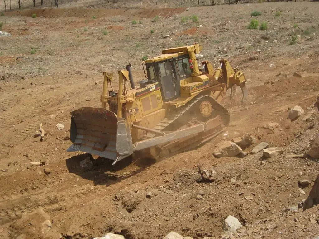 Yellow Bulldozer Pushing Dirt and Rocks Uphill on A Construction Site — STJ Earthmoving in Mareeba, QLD