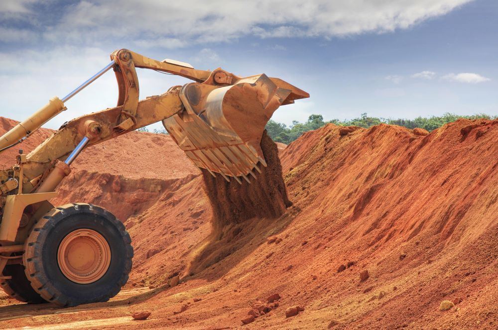 Yellow Excavator Dumping Red Soil on a Hillside, Under a Partly Cloudy Sky — STJ Earthmoving in Hann River, QLD