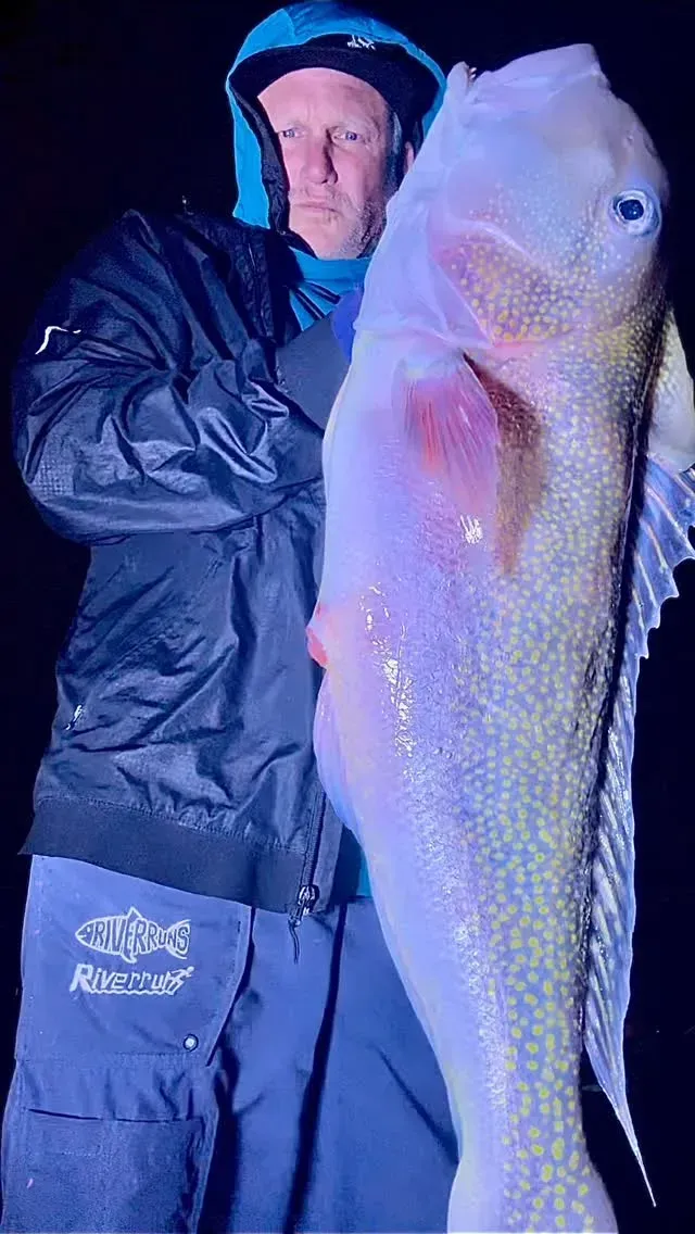 A man is holding a large fish in his hands.