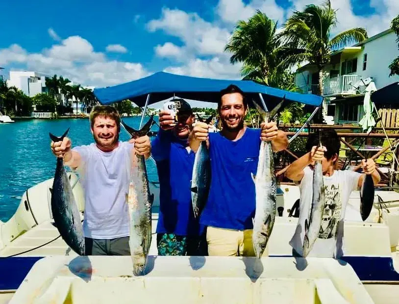 A group of men on a boat holding fish in their hands