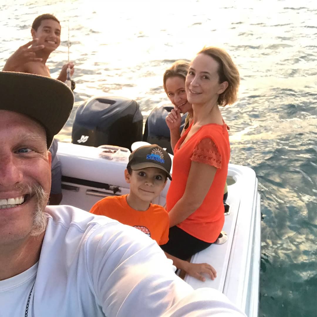 A group of people on a boat with one wearing an adidas hat