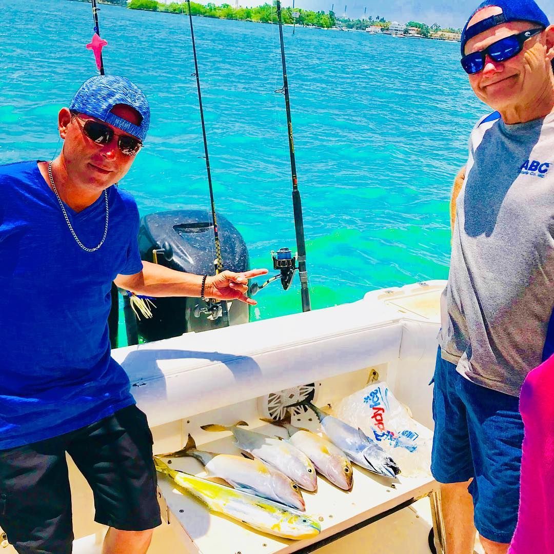 Two men are standing on a boat with fish on the deck.