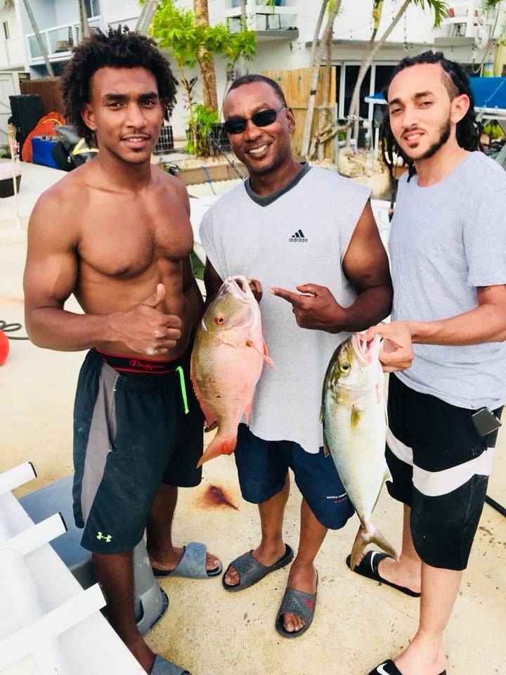 Three men standing next to each other holding large fish