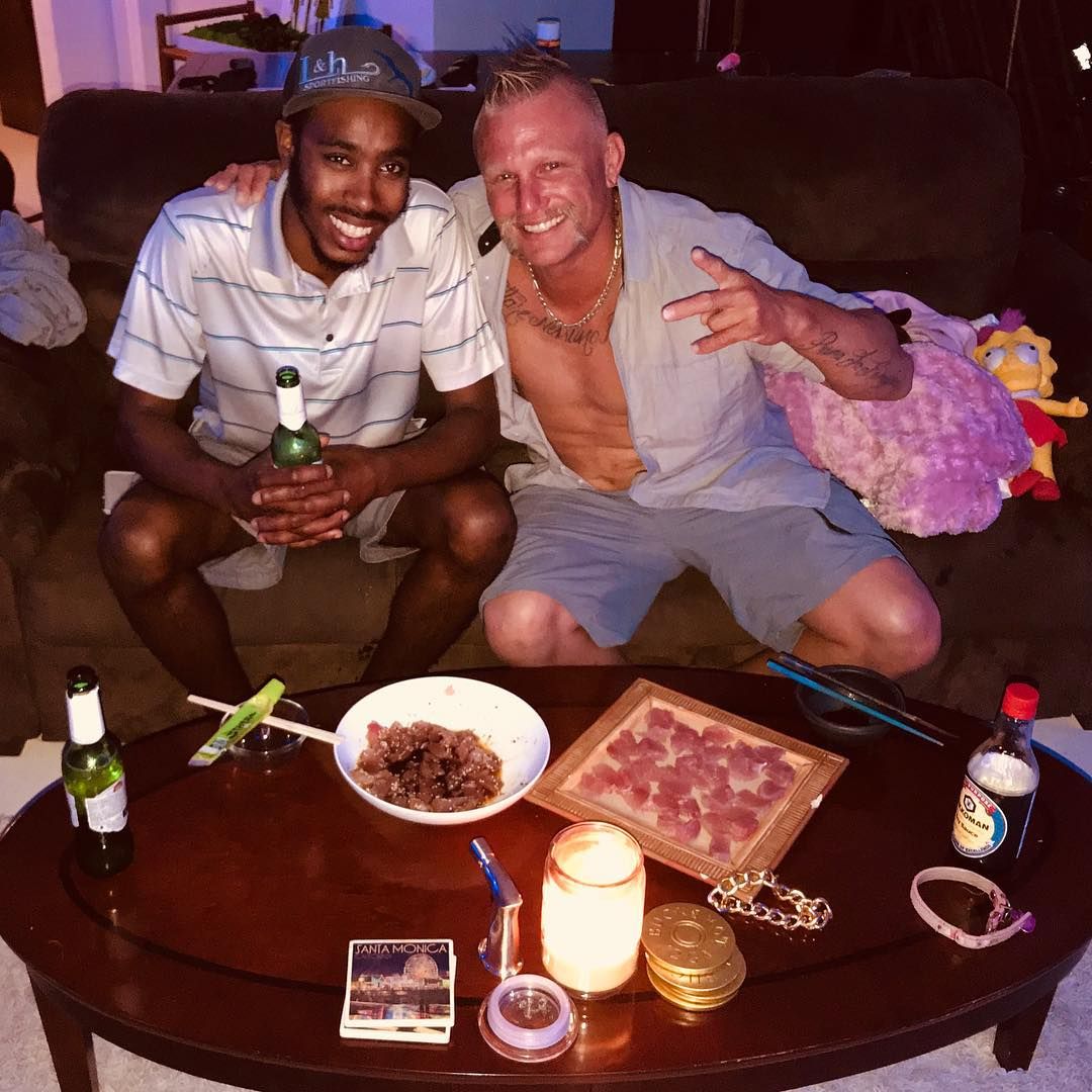 Two men are sitting on a couch and posing for a picture
