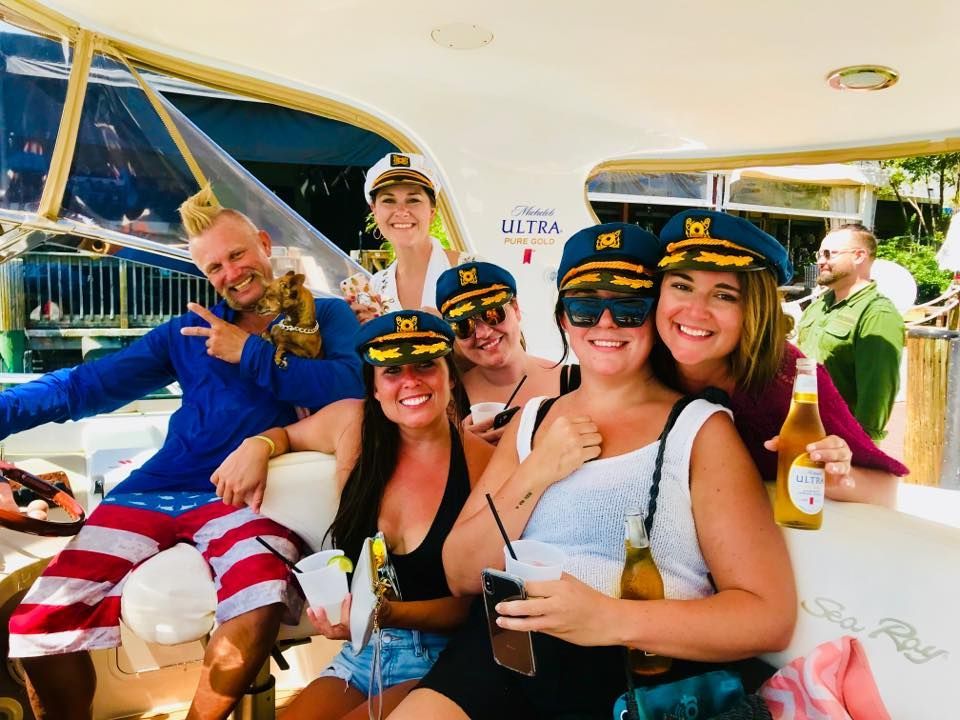 A group of people are sitting on a boat wearing captain hats.