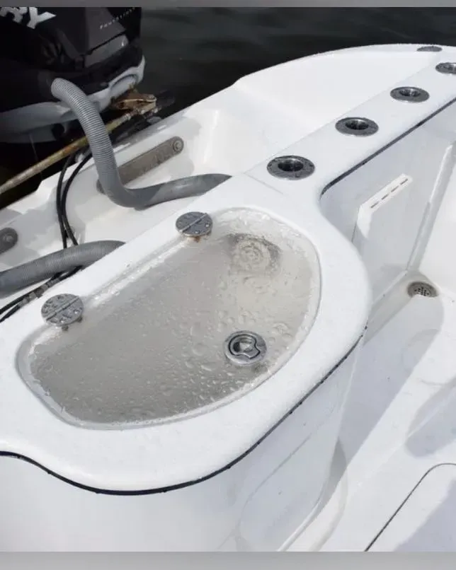 A white boat with a sink and a mercury motor