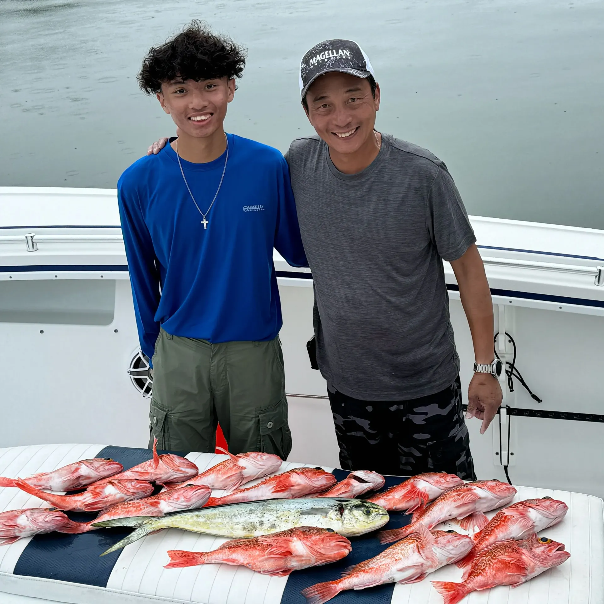 Two men standing next to a table full of fish